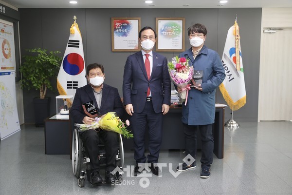 박상돈 천안시장이 23일 임기 만료로 퇴임하는 김형규 장애인체육회 사무국장과 유영근 축구단 사무국장에게 공로패를 전달하고 기념사진을 찍고 있다.(사진제공=천안시청)