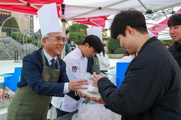24일 정오 목원대 중앙도서관 앞 진리의광장에서 이희학 총장(왼쪽)이 한 학생에게 간식 꾸러미를 전달하고 있다./사진제공=목원대